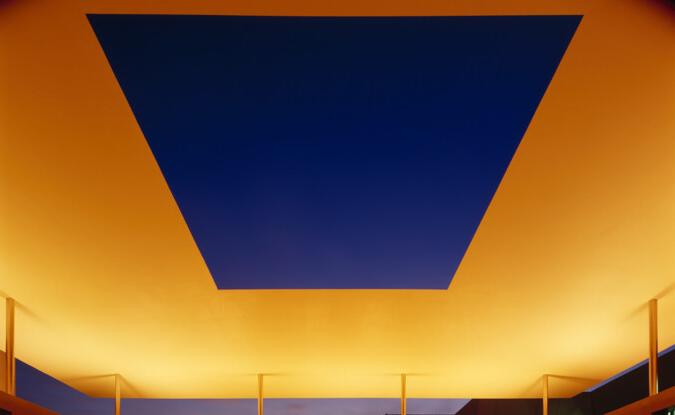 yellow-orange lighting on roof structure with square opening over a pool 