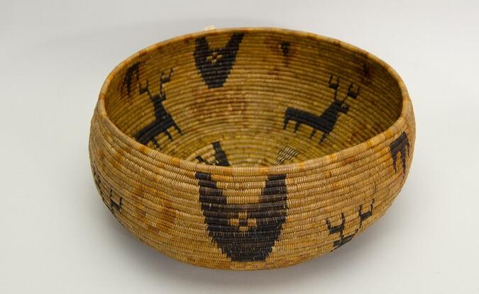 Restricted hemispherical basket with a flat base. Coiled construction. Four black deer with antlers on buff background.